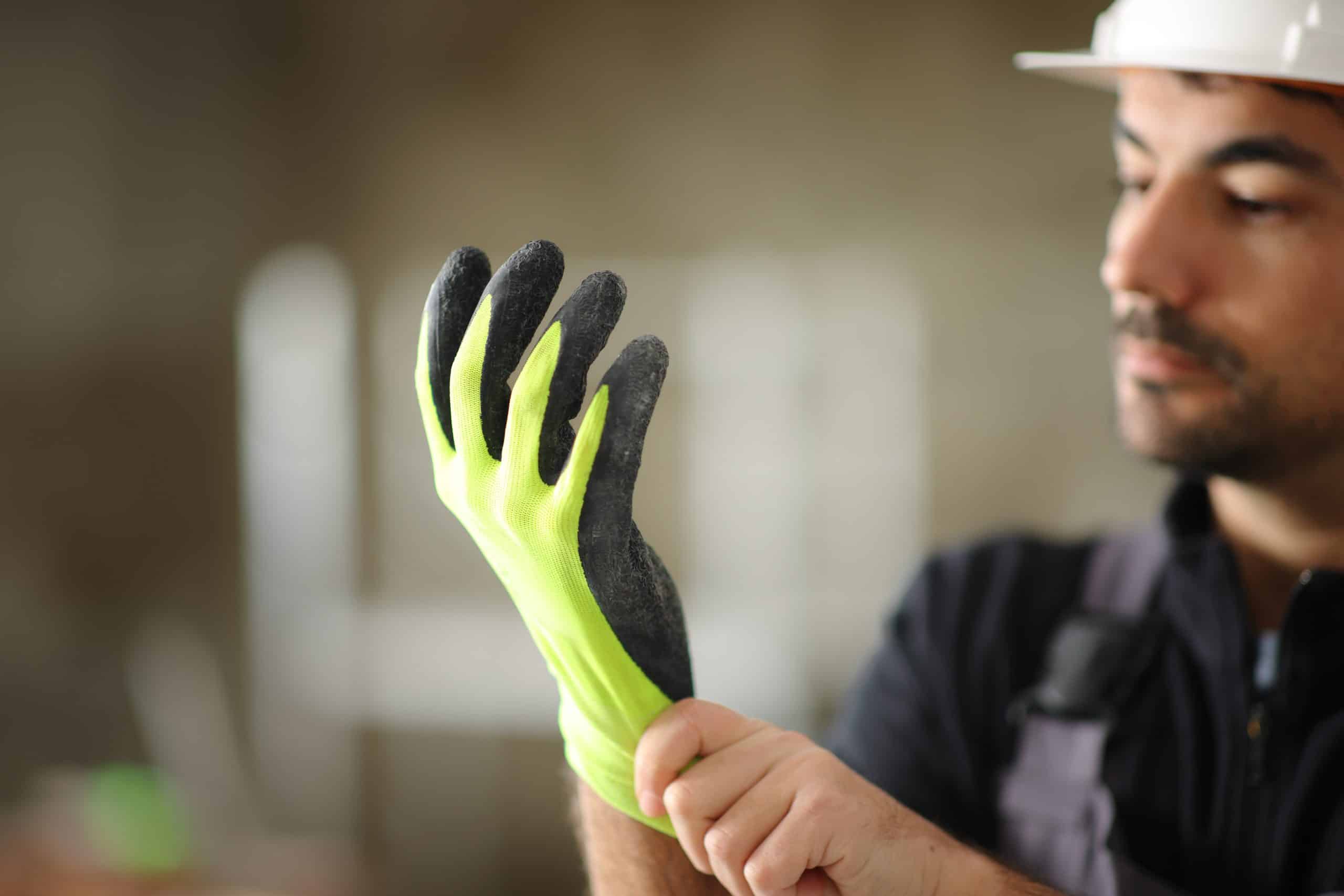 Construction worker putting a yellow protection glove in a house under reform