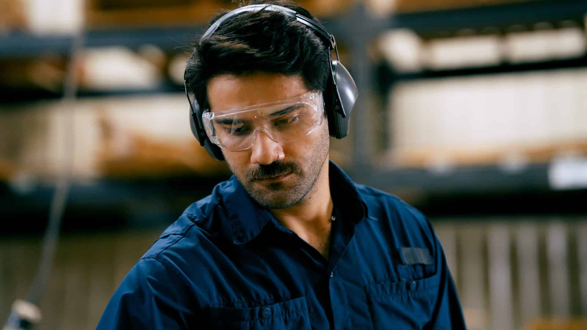 Man focusing on his work, wearing safety glasses and ear muffs for protection
